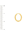 Gold hoop earring next to a ruler on a white background