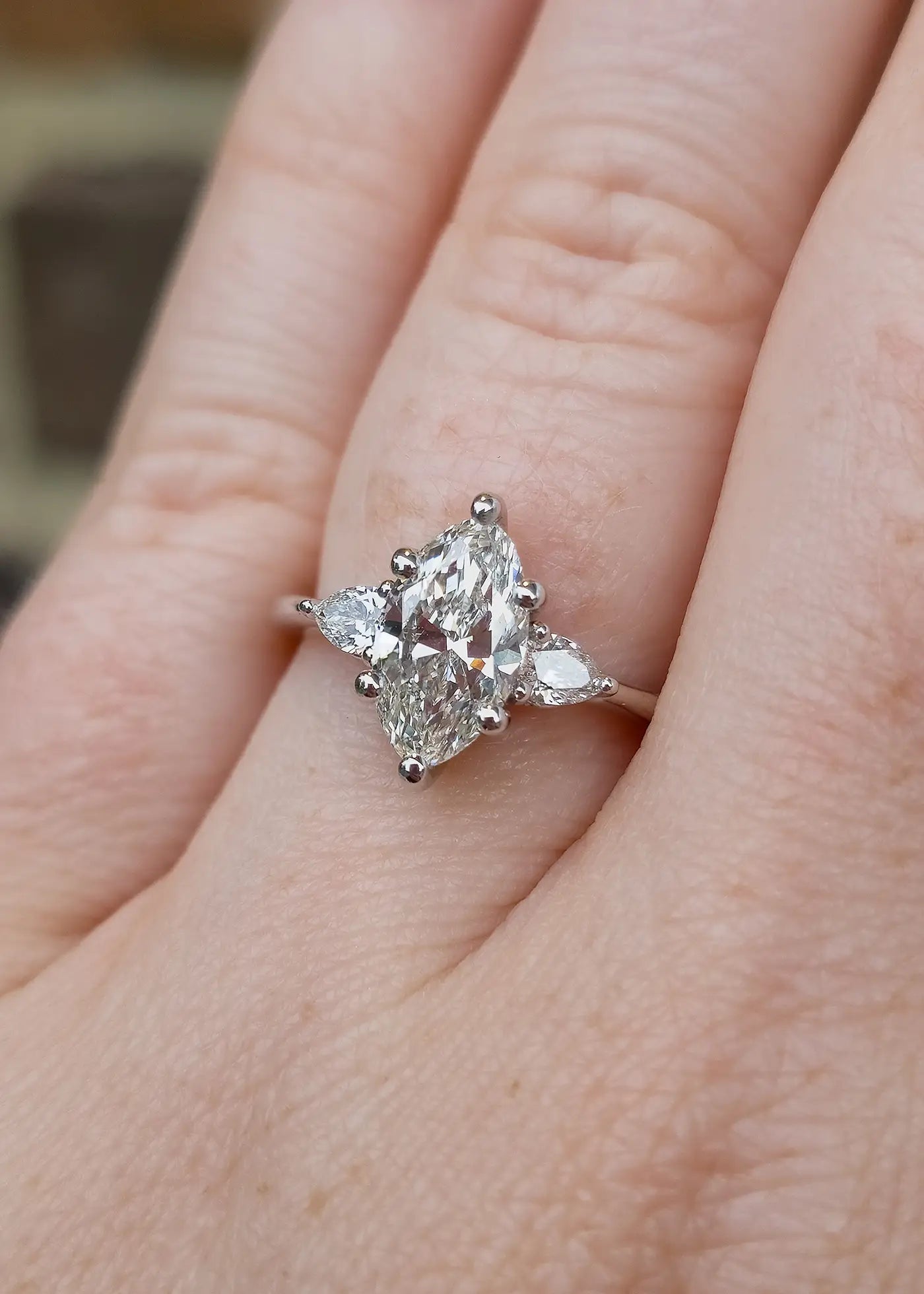 Marquise Diamond engagement ring with triangle side stones on a finger.