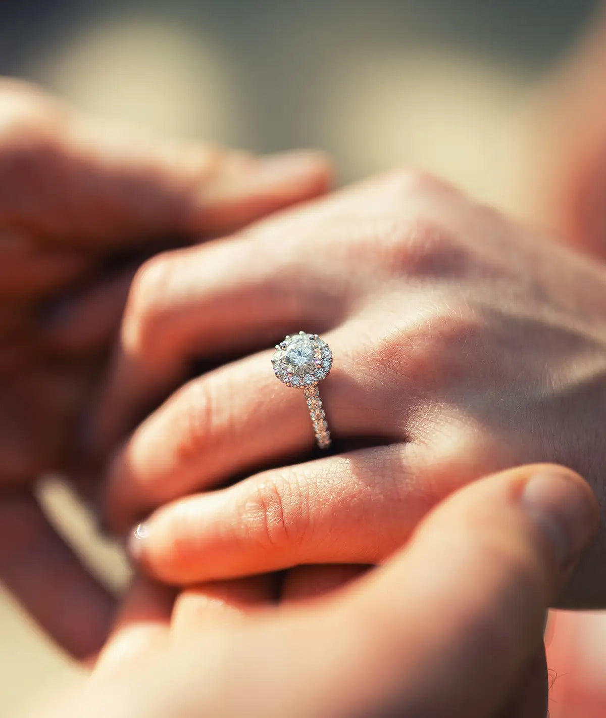 Close-up of a round halo diamond engagement ring on a person's finger.