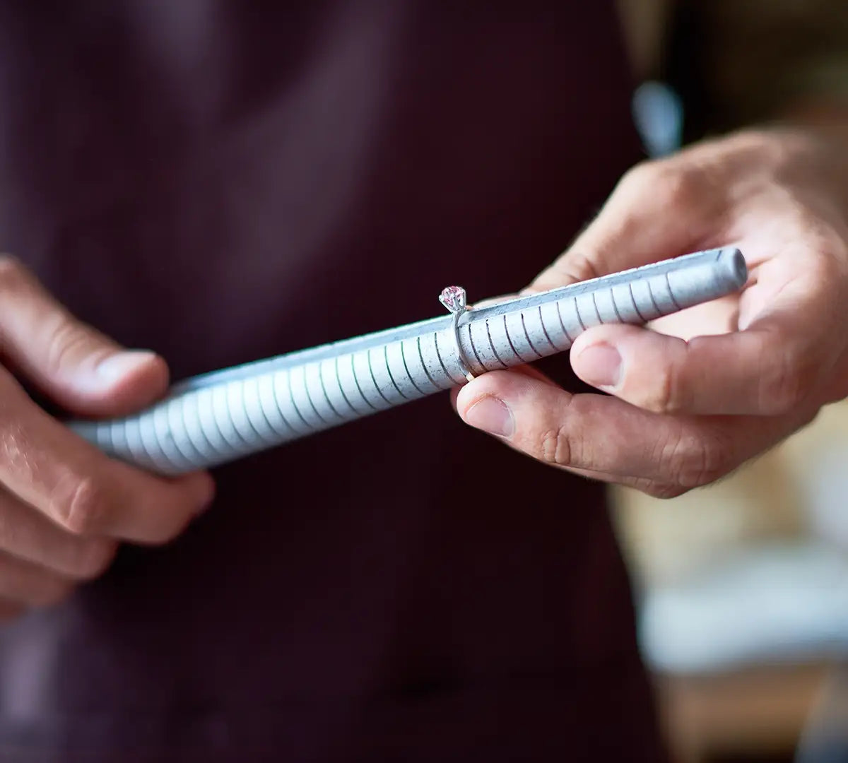 A close-up of a person using a ring sizer tool to see the size of a diamond ring.