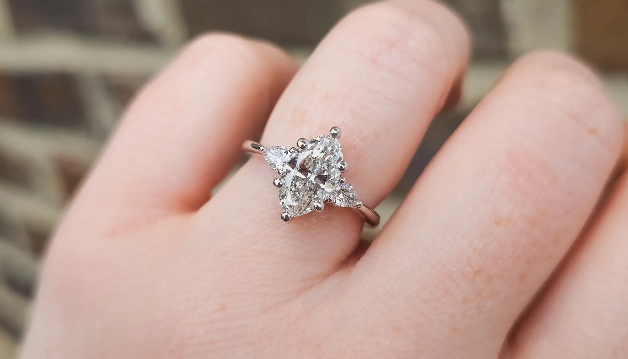 Marquise Diamond engagement ring with triangle side stones on a finger.