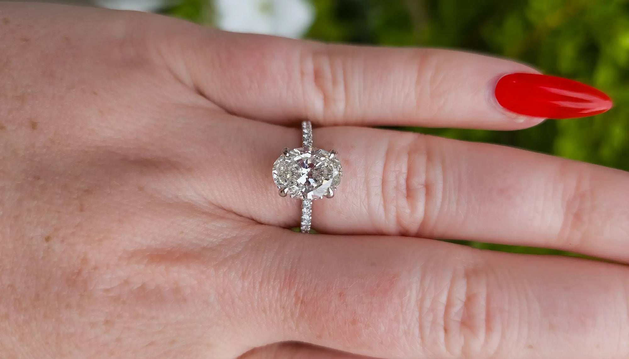 oval diamond claw prong engagement ring with a diamond accented band